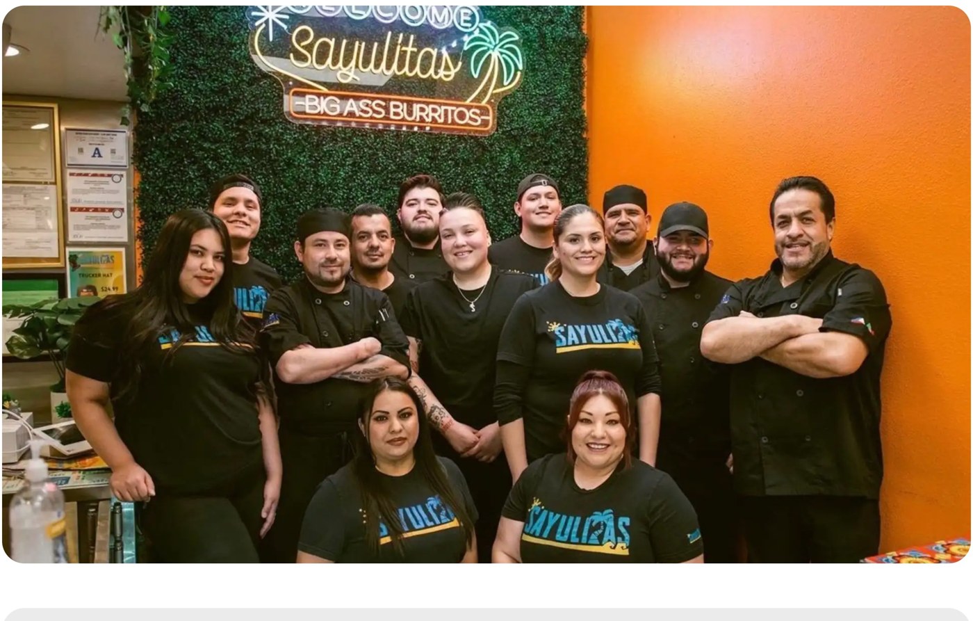 Sayulitas team in front of neon Big Ass Burritos sign